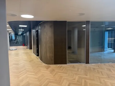 Kontor med glassvegger og trepanel.